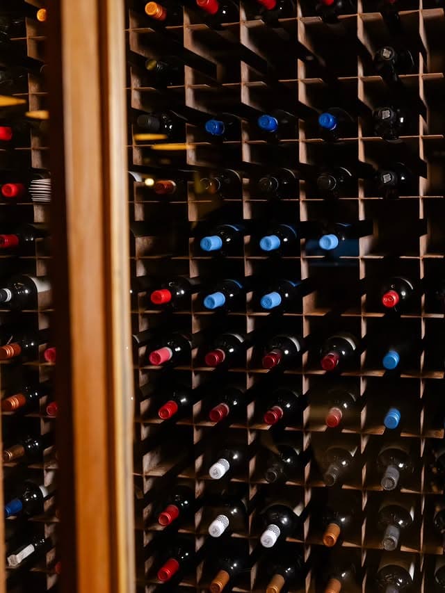 Adega com garrafas de vinho deitadas em nichos de madeira